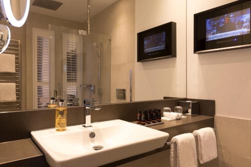 a bathroom with a white sink and a tv at Hotel Brunnenhaus Schloss Landau in Bad Arolsen