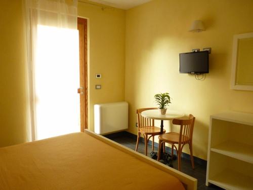 a room with a table and chairs and a tv on the wall at La Gerbera in Levanto