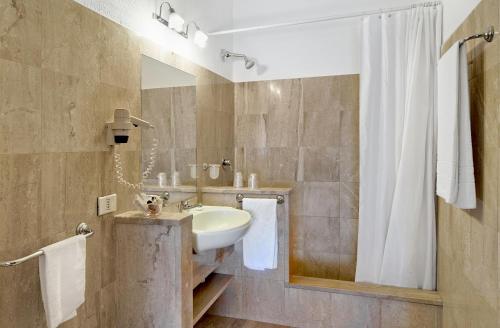 une salle de bain avec un lavabo et une douche dans l'établissement Colonna Palace Hotel Mediterraneo, à Olbia