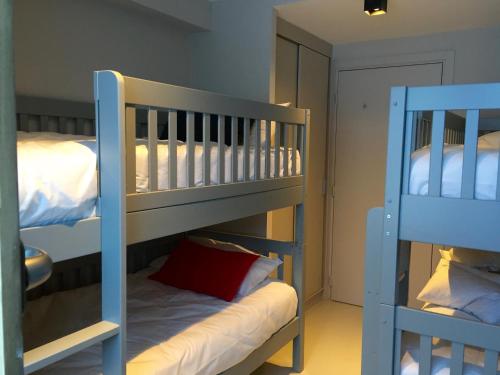 - 2 lits superposés dans une chambre avec un oreiller rouge dans l'établissement Home by U - Chalet 3, à Saint-Martin-de-Belleville