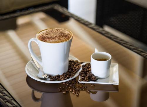 two cups of coffee on a tray with coffee beans at Secret Harbour Boutique Hotel and Marina in Lance aux Épines