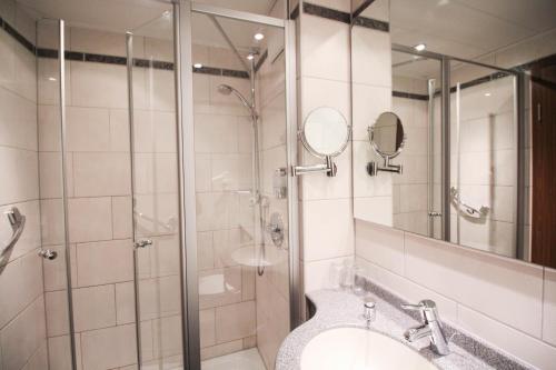 a bathroom with a shower and a sink and a mirror at Hotel-Gasthof Obermeier in Allershausen