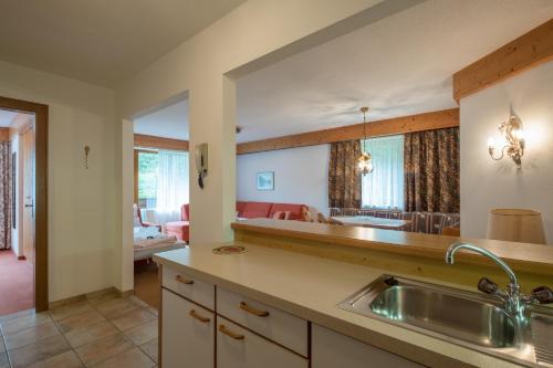 eine Küche mit einem Waschbecken und ein Wohnzimmer in der Unterkunft Haus Montana in Elbigenalp