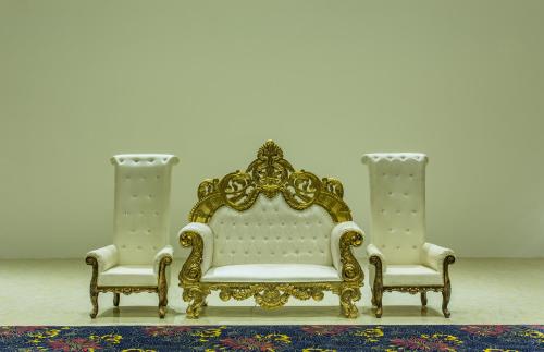 a gold and white couch and two chairs on a rug at Hotel Abika Elite in Ujjain