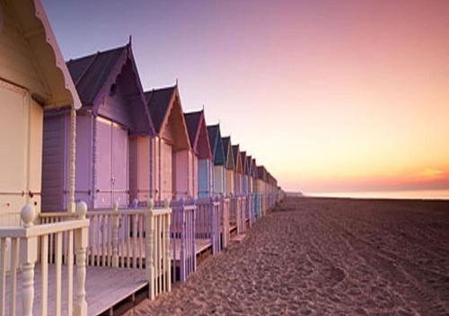 a row of beach houses on the beach at sunset at Romantic Lakeside Cottage by the Beach! with Super Cosy Log Burner! The Perfect Escape to Your Home from Home by the Sea! So Relaxing - You Won't want to Leave! Pet Friendly! in Mablethorpe