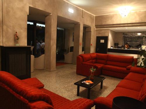 a living room with red couches and a table at Hotel Pineta in Cagli