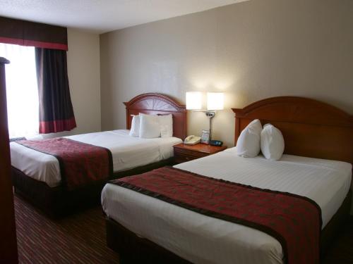 a hotel room with two beds and a phone at Baymont by Wyndham Louisville East in Louisville