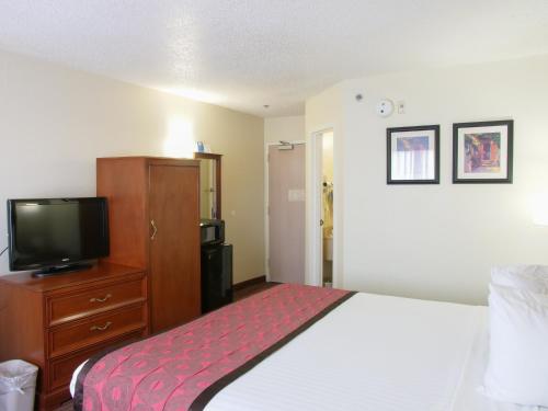 a hotel room with a bed and a tv at Baymont by Wyndham Louisville East in Louisville