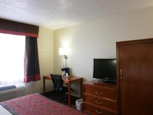 a hotel room with a bed and a television and a desk at Baymont by Wyndham Louisville East in Louisville