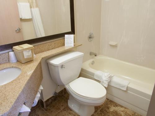 a bathroom with a toilet and a sink and a tub at Baymont by Wyndham Louisville East in Louisville