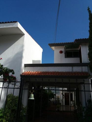 a white house with a black fence and a bell at Room in Cancun Stadium in Cancún
