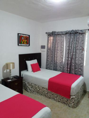 a bedroom with two beds with red and white sheets at Room in Cancun Stadium in Cancún