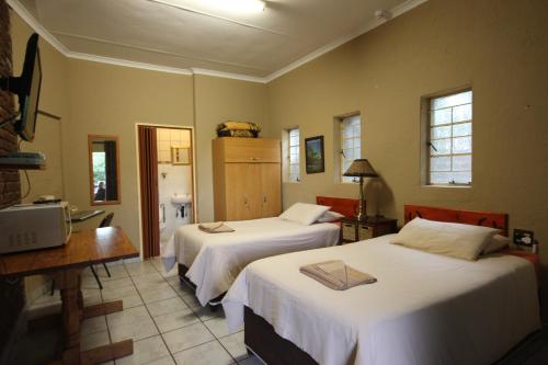 um quarto com 2 camas, uma mesa e uma secretária em Ingwe Guesthouse em Nelspruit