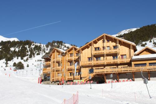 a large wooden building on a ski slope in the snow at Anova Hotel & Spa in Montgenèvre