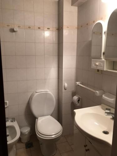 a white bathroom with a toilet and a sink at Departamento amoblado en pleno centro, con cochera in Bahía Blanca