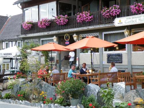 eine Gruppe von Menschen, die in einem Restaurant mit Sonnenschirmen sitzen in der Unterkunft Gasthof Müller in Winterberg