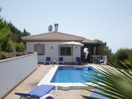 - une piscine avec des chaises et une maison dans l'établissement Villa Competa, à Cómpeta
