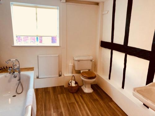 a bathroom with a toilet and a tub and a window at The Dorset Arms Pub & Cottage Rooms in Groombridge