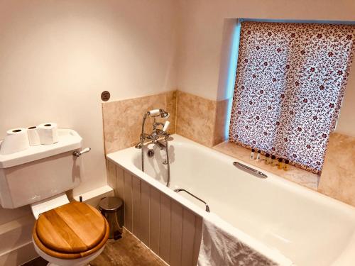 a bathroom with a toilet and a bath tub at The Dorset Arms Pub & Cottage Rooms in Groombridge