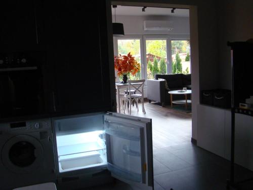 an open refrigerator in a kitchen with a living room at Apartament Honey in Polanica-Zdrój
