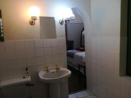een badkamer met een wastafel, een toilet en een bed bij House On Plein in Paarl