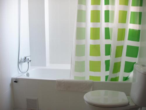 um banheiro com cortina de chuveiro verde e branca e um vaso sanitário em Apartamentos Maria Victoria em Benidorm