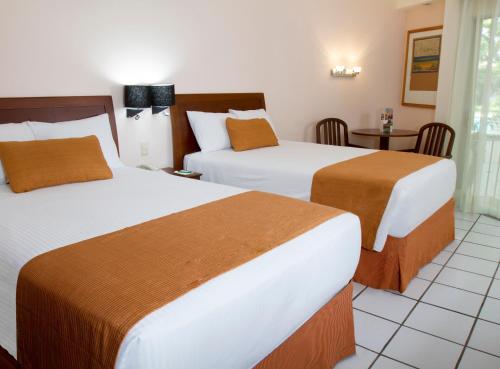 a hotel room with two beds and a table at Hotel Viva Villahermosa in Villahermosa