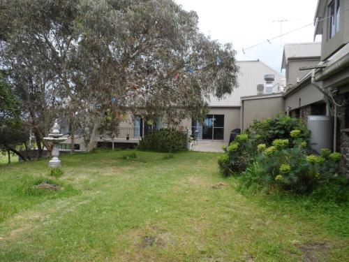 a yard in front of a house with a tree at Swan Lake Guest House in Ventnor