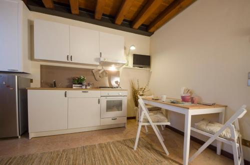 cocina con armarios blancos, mesa y escritorio en Il Salice, en Treviso