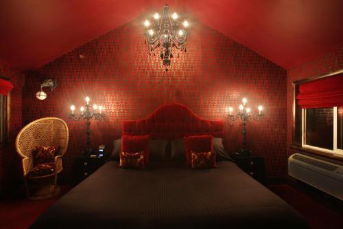 a red bedroom with a bed and a chandelier at The Roxbury in Roxbury