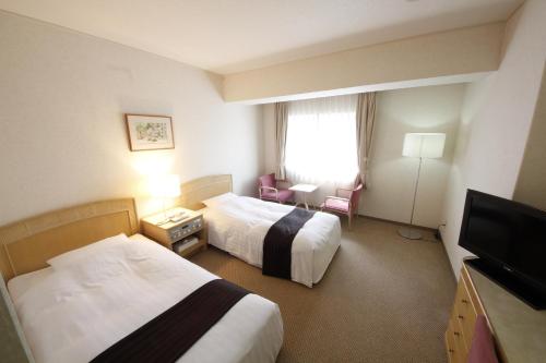 a hotel room with two beds and a flat screen tv at Hotel Hiroshima Garden Palace in Hiroshima