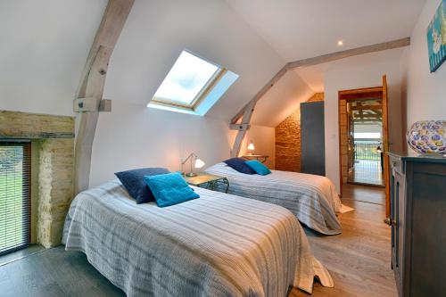 a bedroom with two beds and a skylight at Le Domaine du Douet du Houle, Piscine & SPA, 2-19p in Courcy