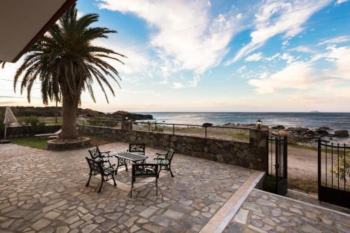 a patio with a table and chairs next to the ocean at Pericles Beach Villa in Kissamos
