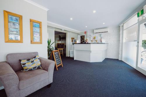 a living room with a chair and a counter at Artesian Spa Motel in Moree
