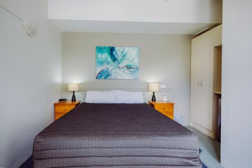 a bedroom with a bed and a painting on the wall at Artesian Spa Motel in Moree