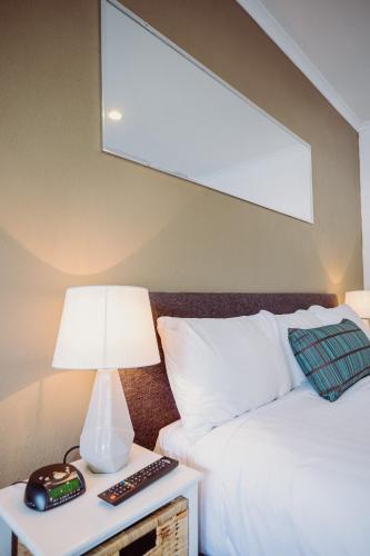 a bed with a lamp and a clock on a night stand at Artesian Spa Motel in Moree
