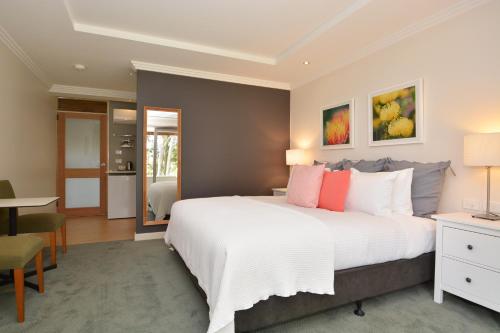 a bedroom with a large white bed and a desk at Elfin Hill Vineyard Accommodation in Pokolbin