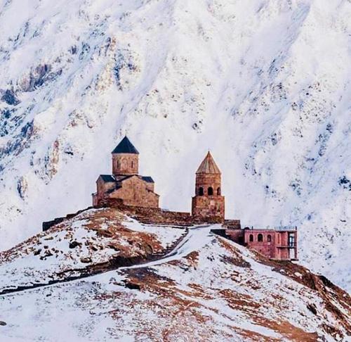 un château au sommet d'une montagne enneigée dans l'établissement Nino Khetaguri Guest House, à Kazbegi