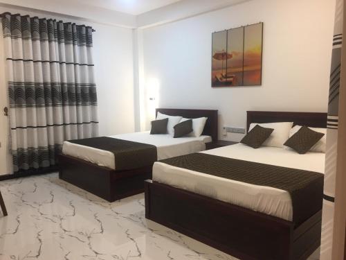 una camera d'albergo con due letti e una finestra di Blue Wings Beach Hotel a Trincomalee