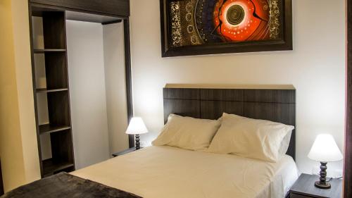 a bedroom with a bed with two lamps and a mirror at Hotel Viña Del Mar in Santa Marta