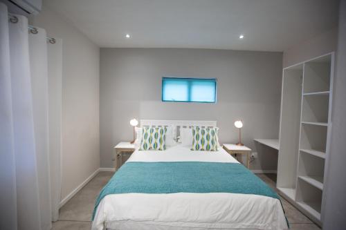 a bedroom with a bed and two tables and shelves at Maya Manor in Hoedspruit