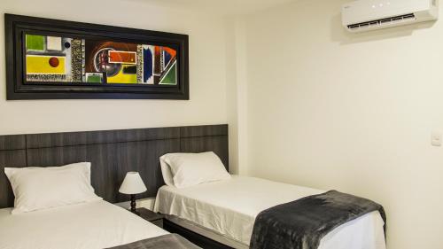 a bedroom with two beds and a tv on the wall at Hotel Viña Del Mar in Santa Marta
