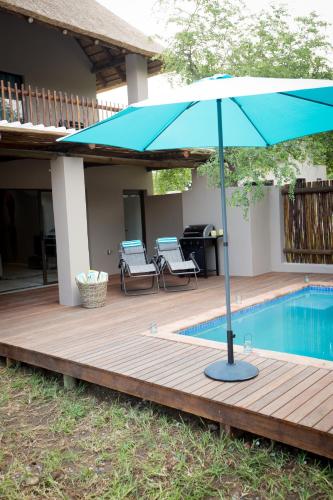 a blue umbrella sitting on a deck next to a pool at Maya Manor in Hoedspruit