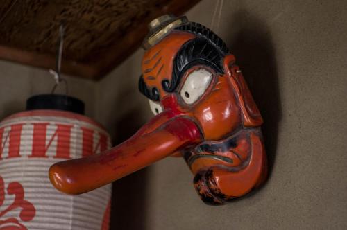 a mask hanging on a wall next to a lamp at 88 House Hiroshima in Hiroshima