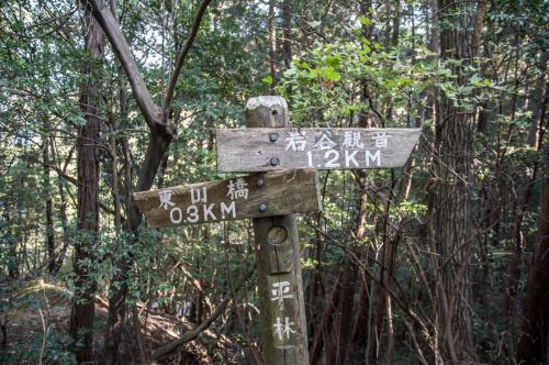 a wooden sign in the middle of a forest at 88 House Hiroshima in Hiroshima