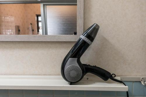 a black hairbrush sitting on a shelf in a bathroom at 88 House Hiroshima in Hiroshima