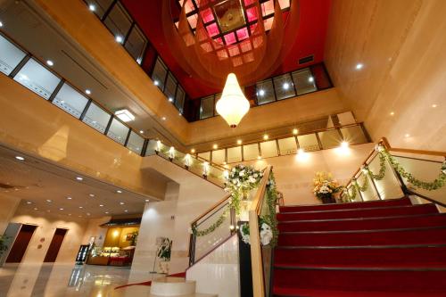 a lobby with a red staircase and a ceiling at Hotel Hiroshima Garden Palace in Hiroshima