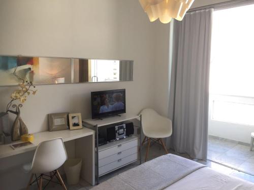 een slaapkamer met een bed en een bureau met een televisie bij Copacabana: lounge lindo, confortável e com vista do mar in Rio de Janeiro