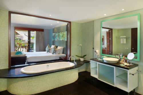 een badkamer met een groot bad en een bed bij Novotel Bali Nusa Dua in Nusa Dua