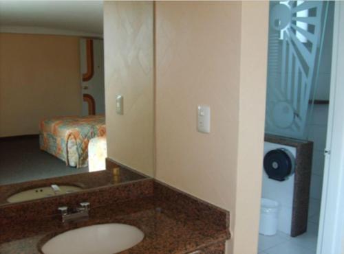 a bathroom with a sink and a bed and a mirror at Hotel Terminal de Puebla in Puebla